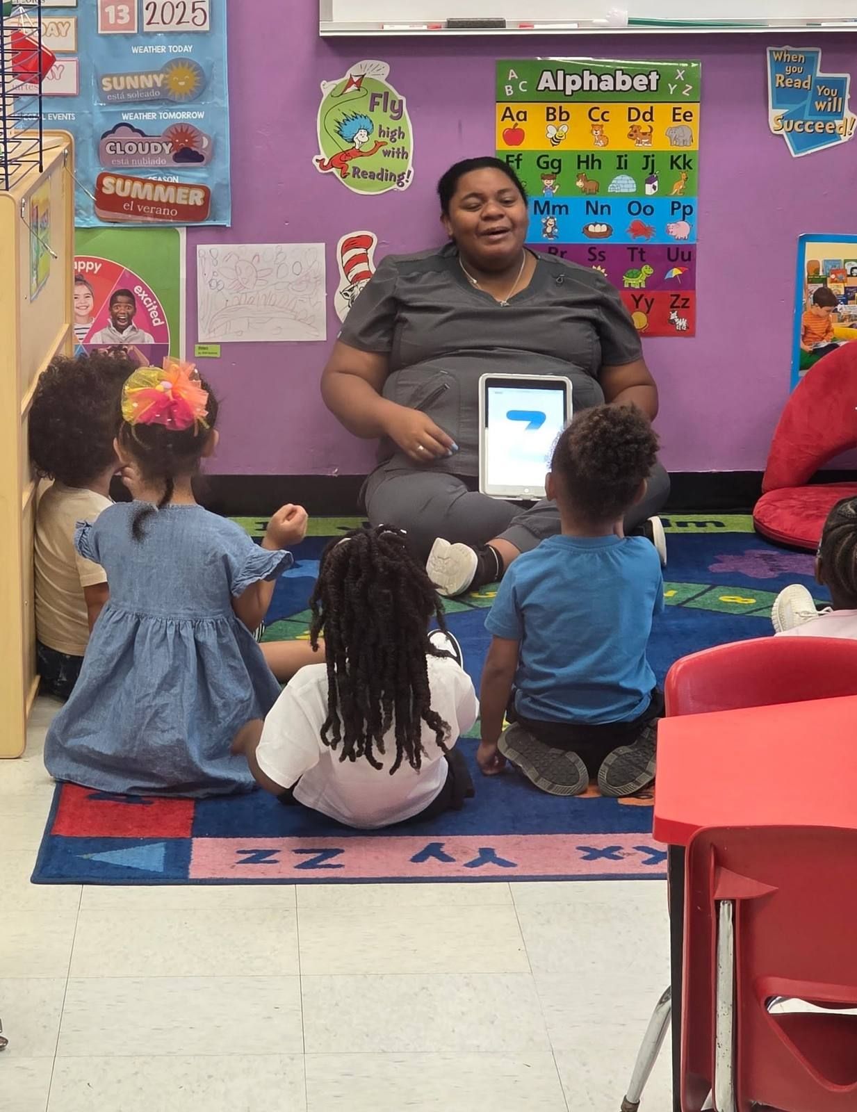 A teacher leading circle time with a letter card while the class sits on the rug