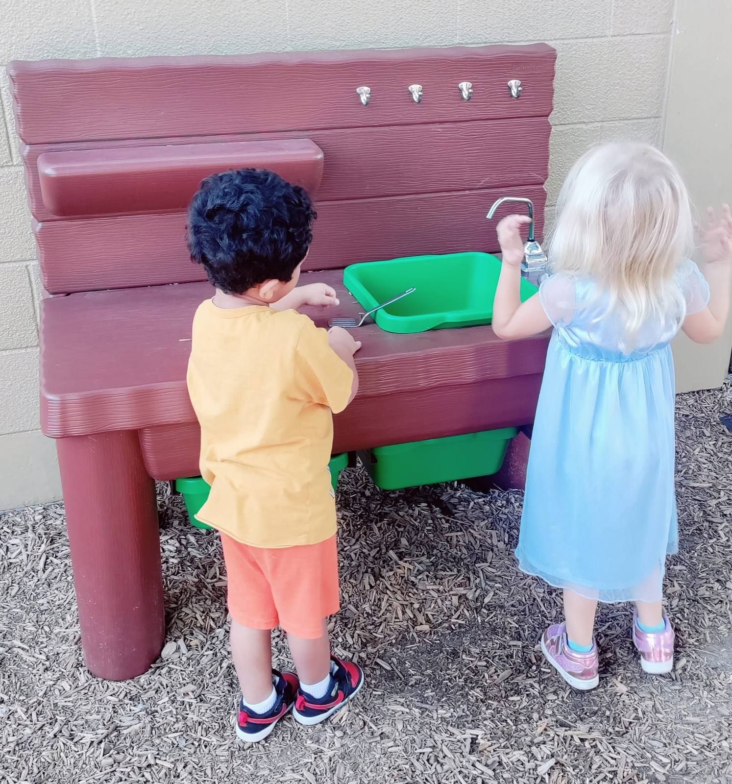 Two kids playing at the outdoor mud kitchen