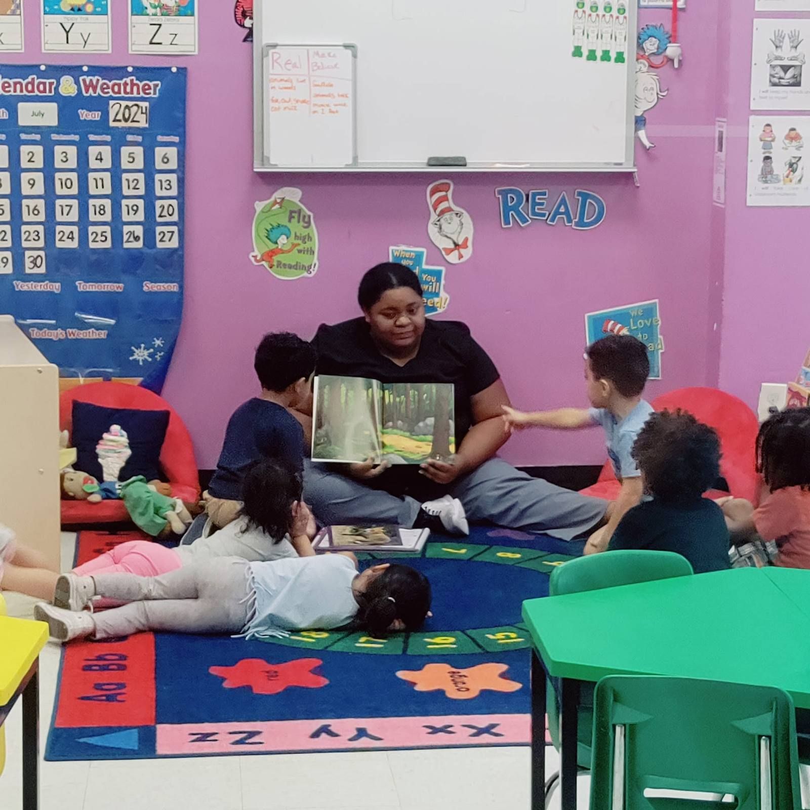 A teacher reading a book to preschoolers relaxing on the rug