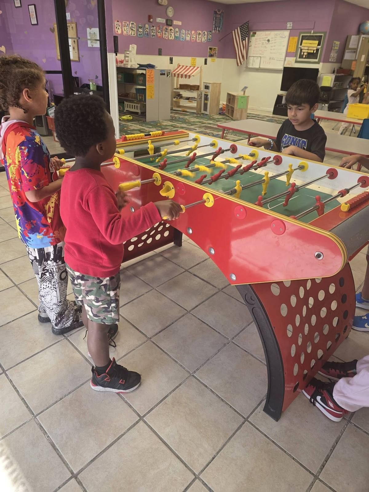 School age kids playing a game of foosball