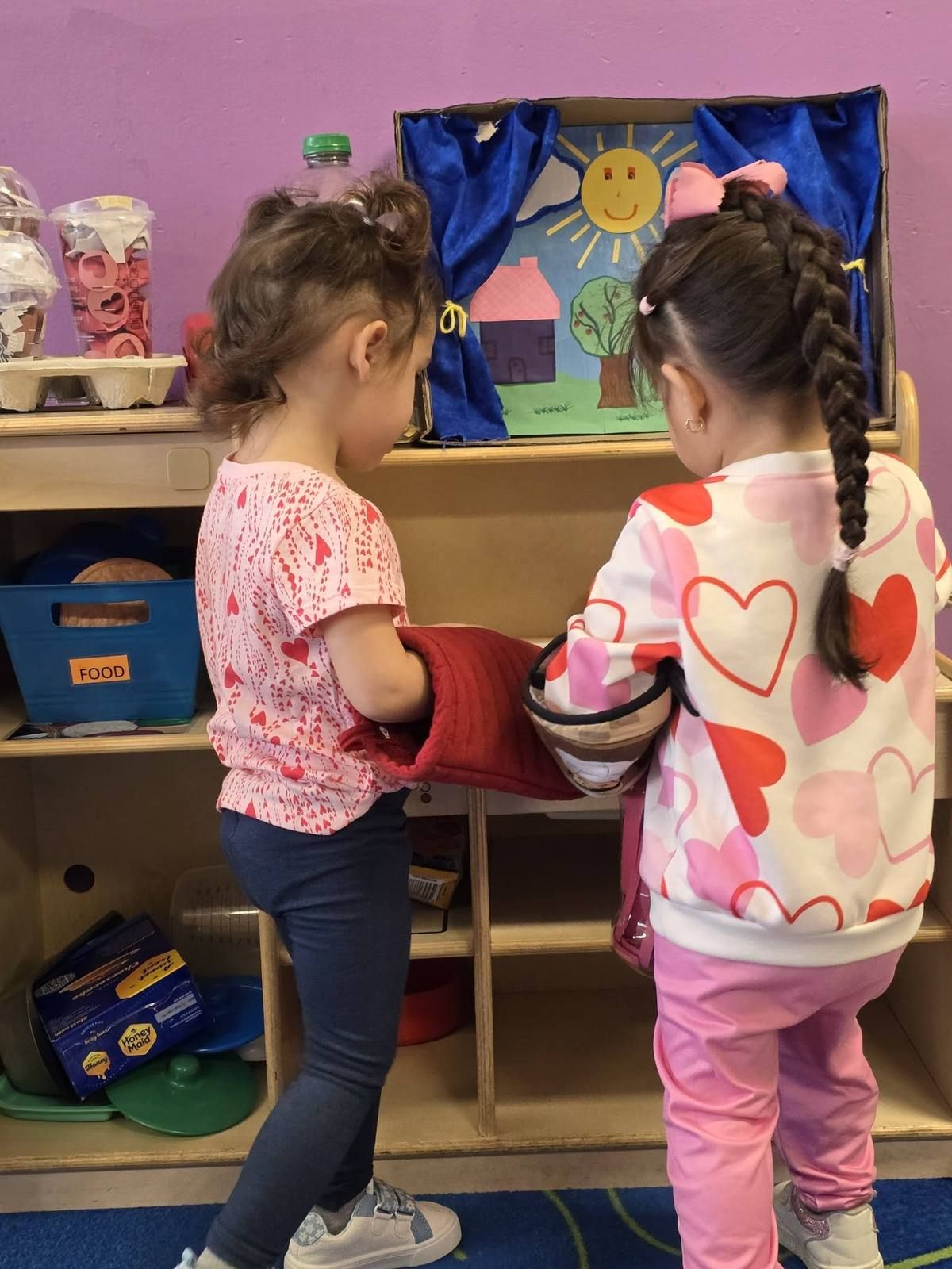 Two little girls cooking with oven mitts in the play kitchen