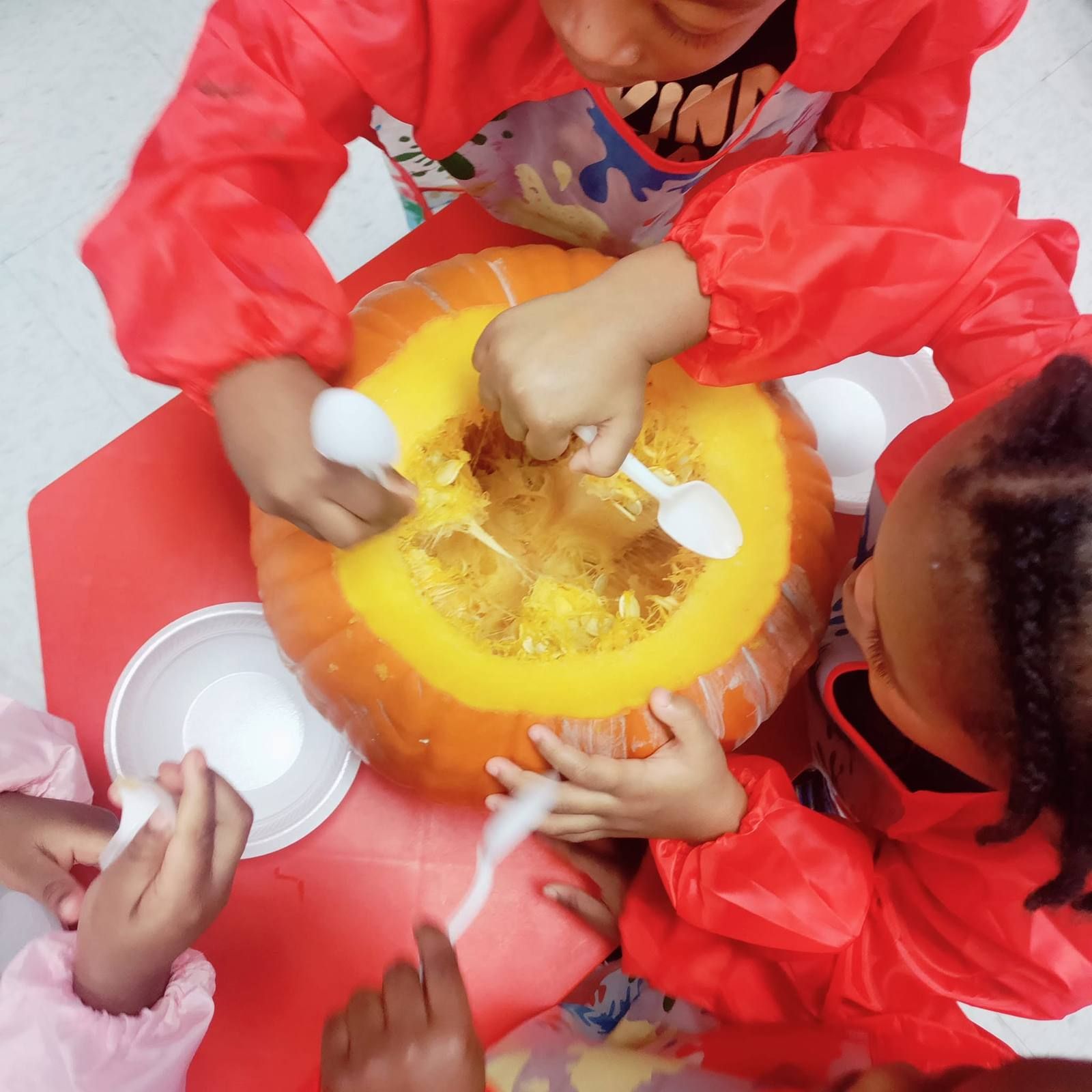 Kids scooping out a pumpkin with spoons