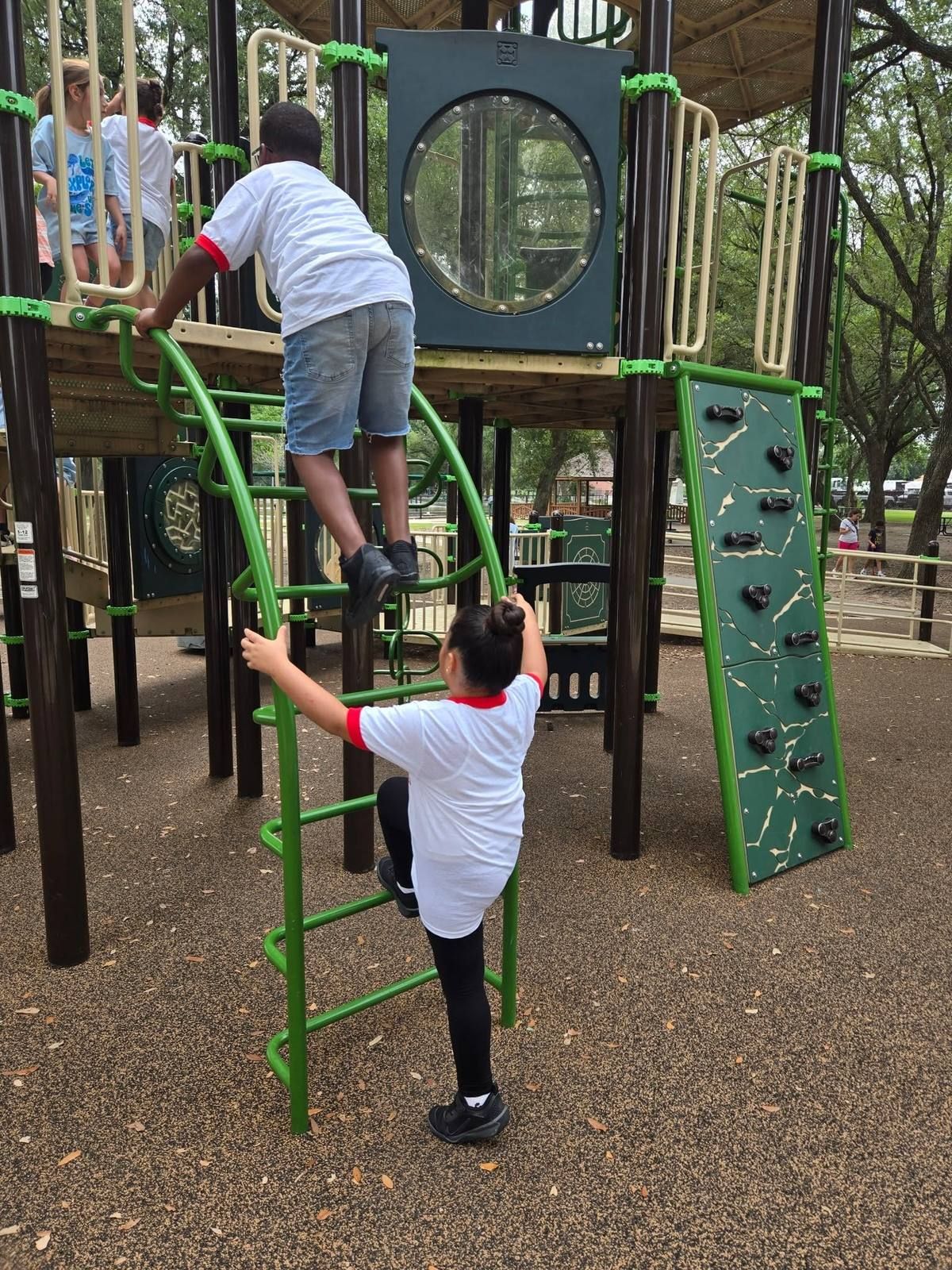 Two Kidco kids climbing a playground ladder