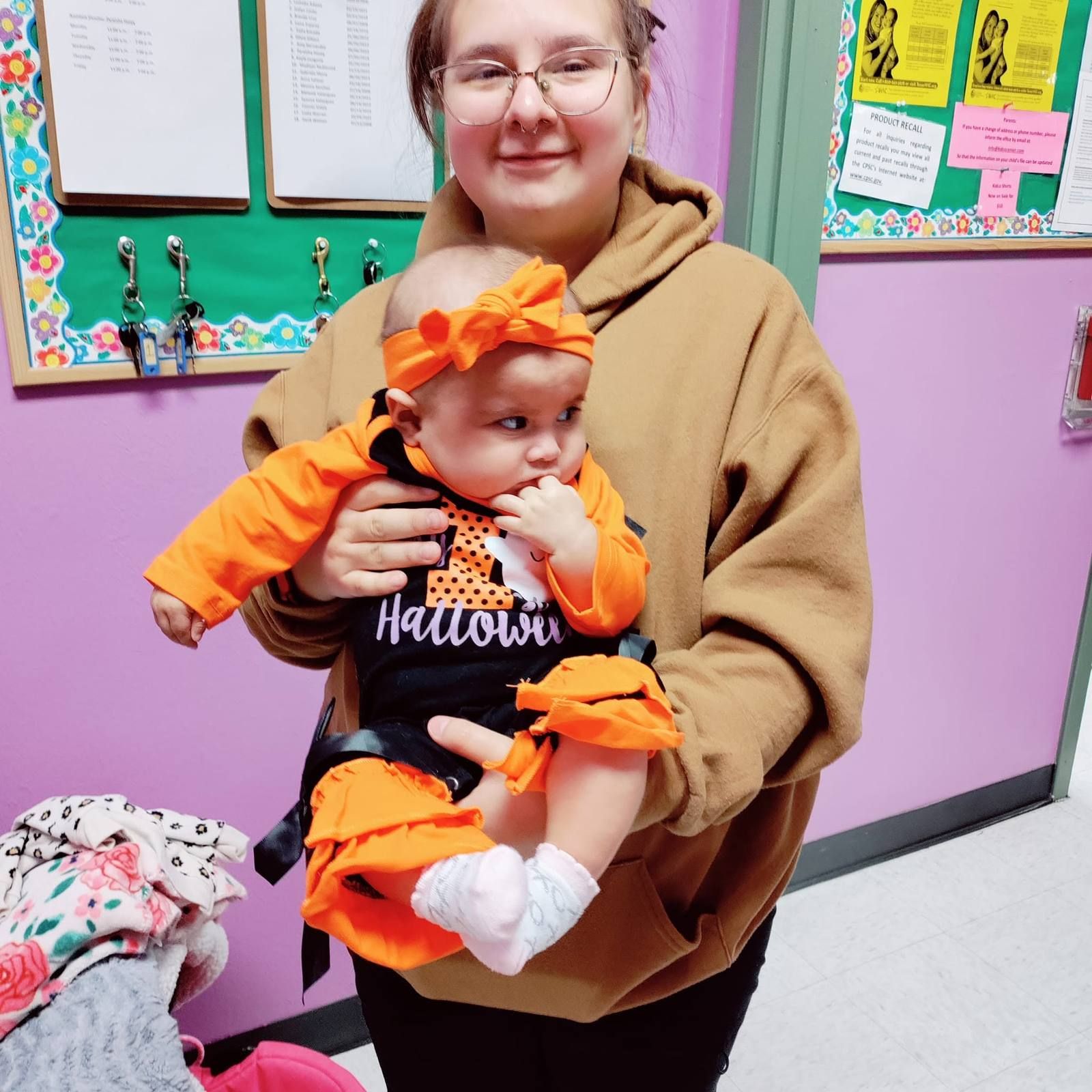 A teacher holding a baby dressed up for Halloween