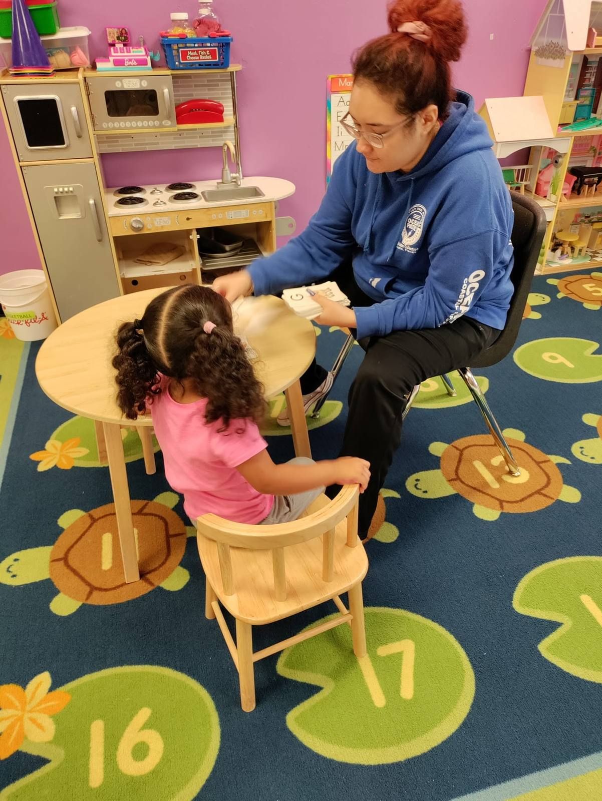 A teacher working one on one with a toddler at a small table