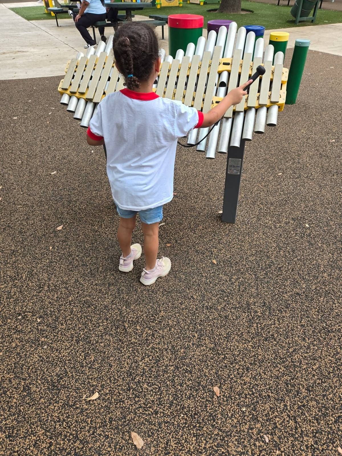 A child playing an outdoor xylophone at the park