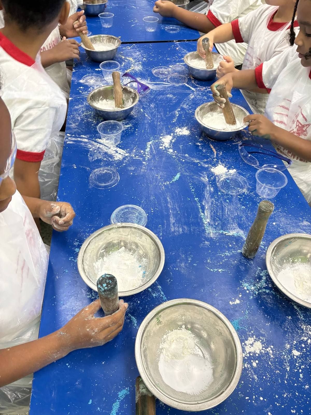 Kids using wooden pestles to grind flour at a hands-on activity table