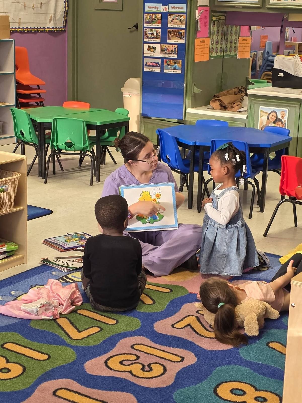 A teacher sharing a picture book with preschoolers on the rug