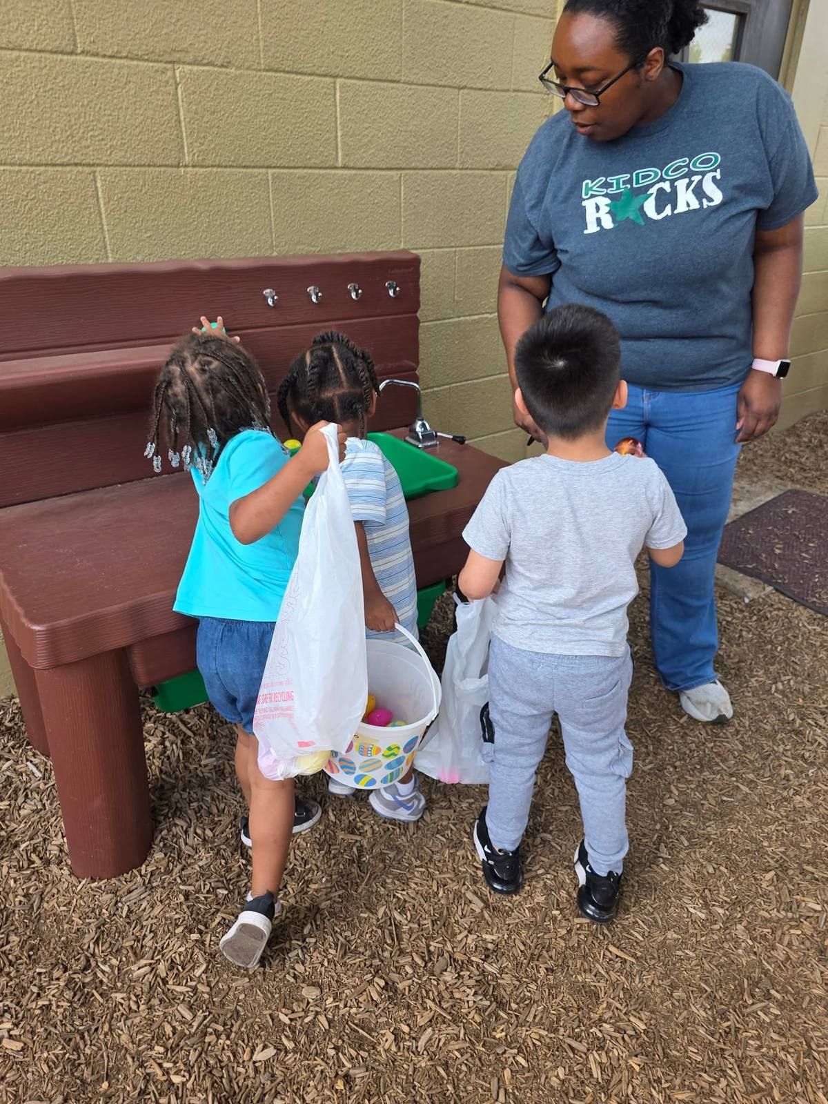 A teacher with kids at the outdoor play sink