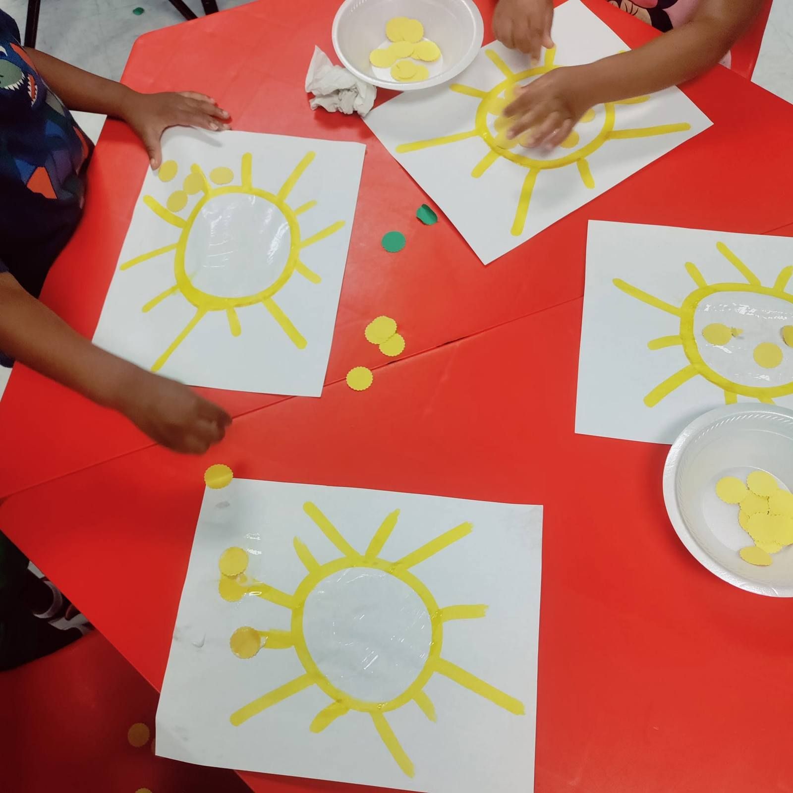 Kids decorating paper suns with yellow dots