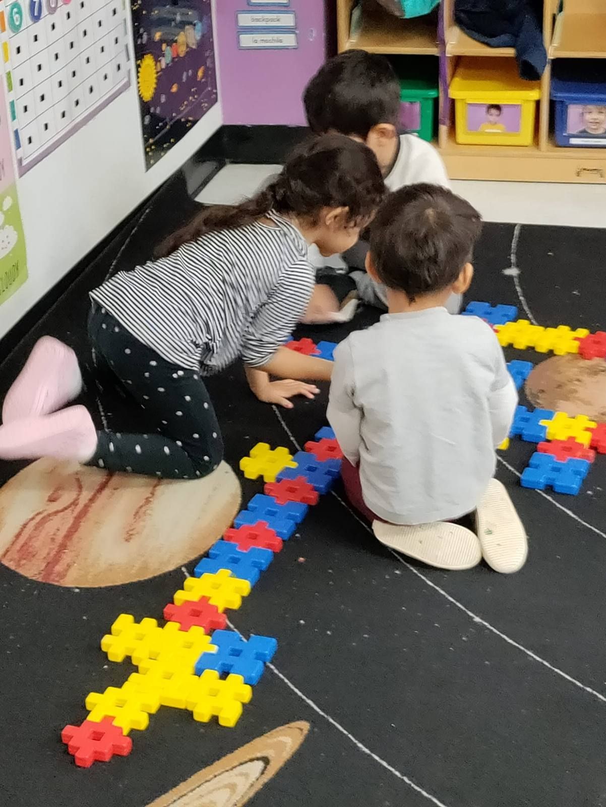 Preschoolers building a long chain with snap-together blocks