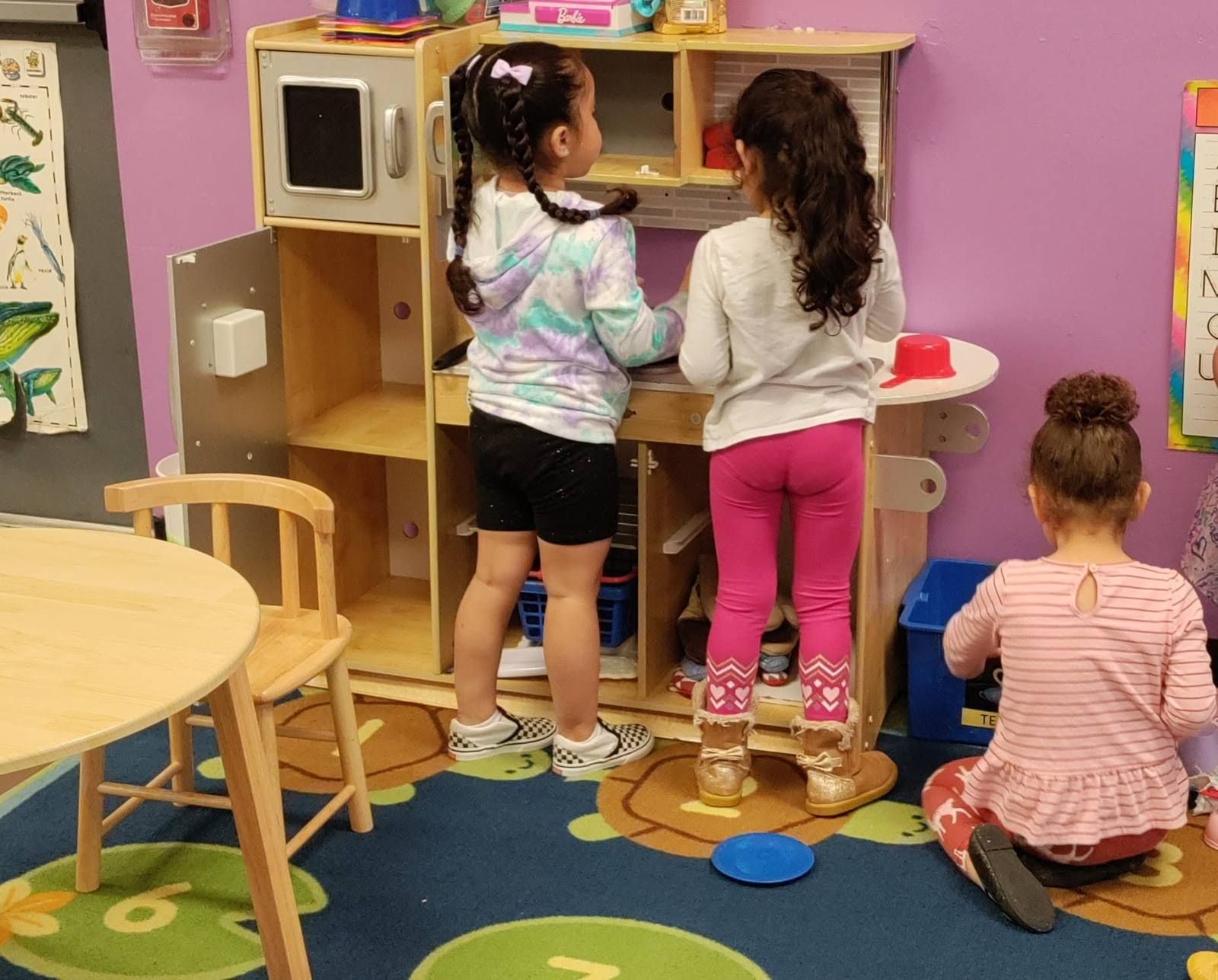 Three girls playing in the classroom kitchen center