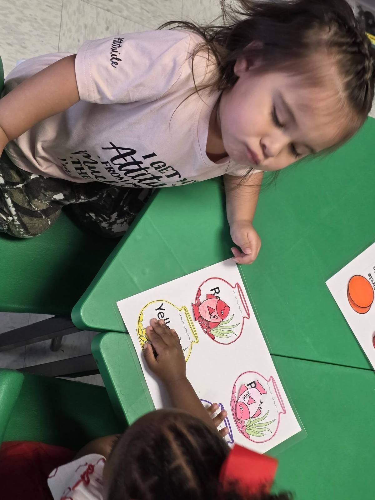 A girl coloring a fish worksheet at the table