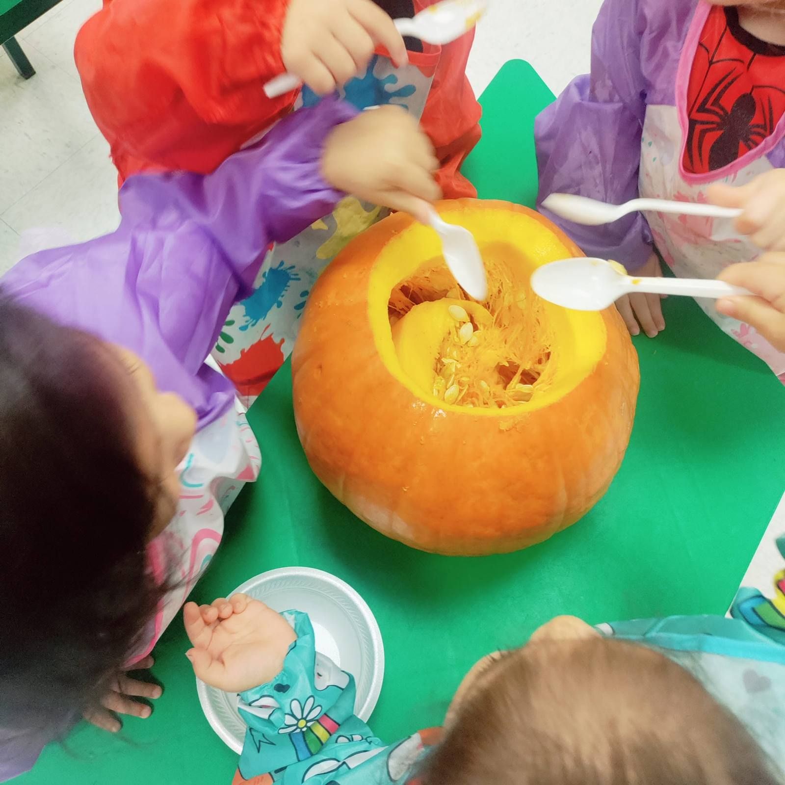 Toddlers scooping pumpkin seeds with spoons