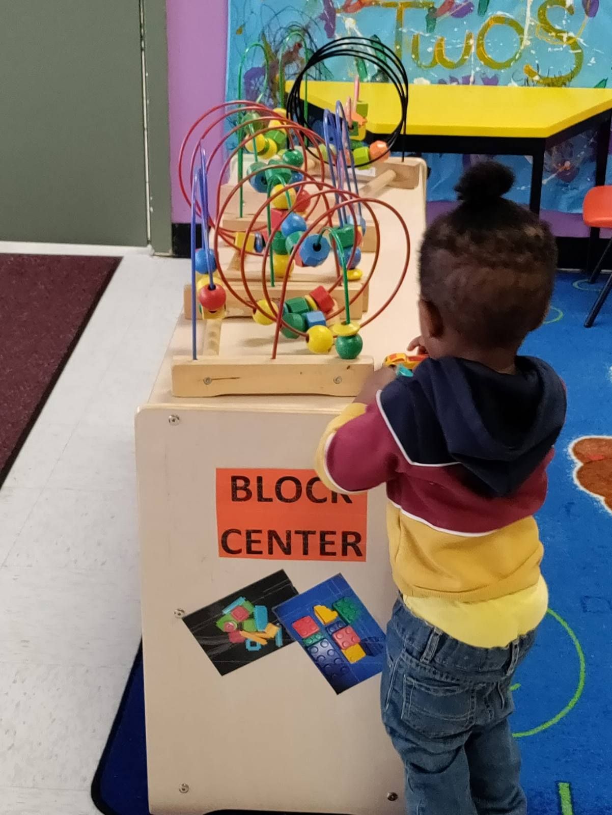 A toddler playing at the bead maze in the block center