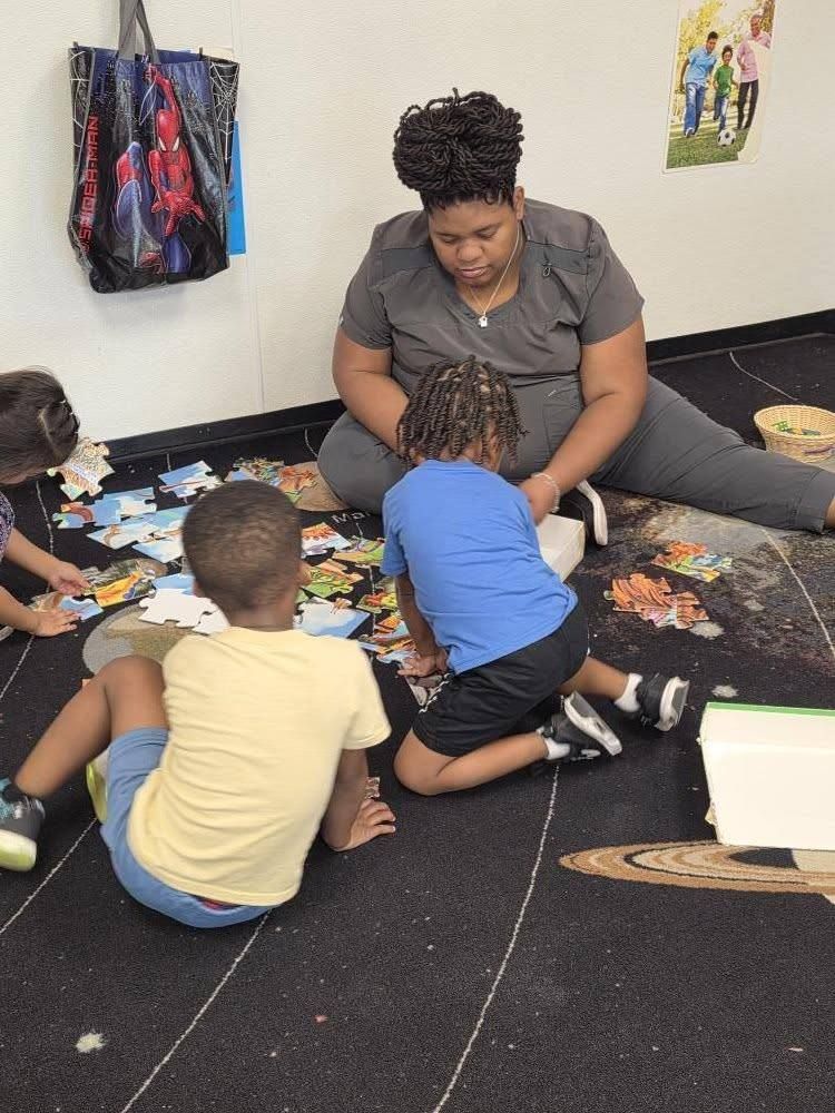 A teacher doing a floor puzzle with toddlers