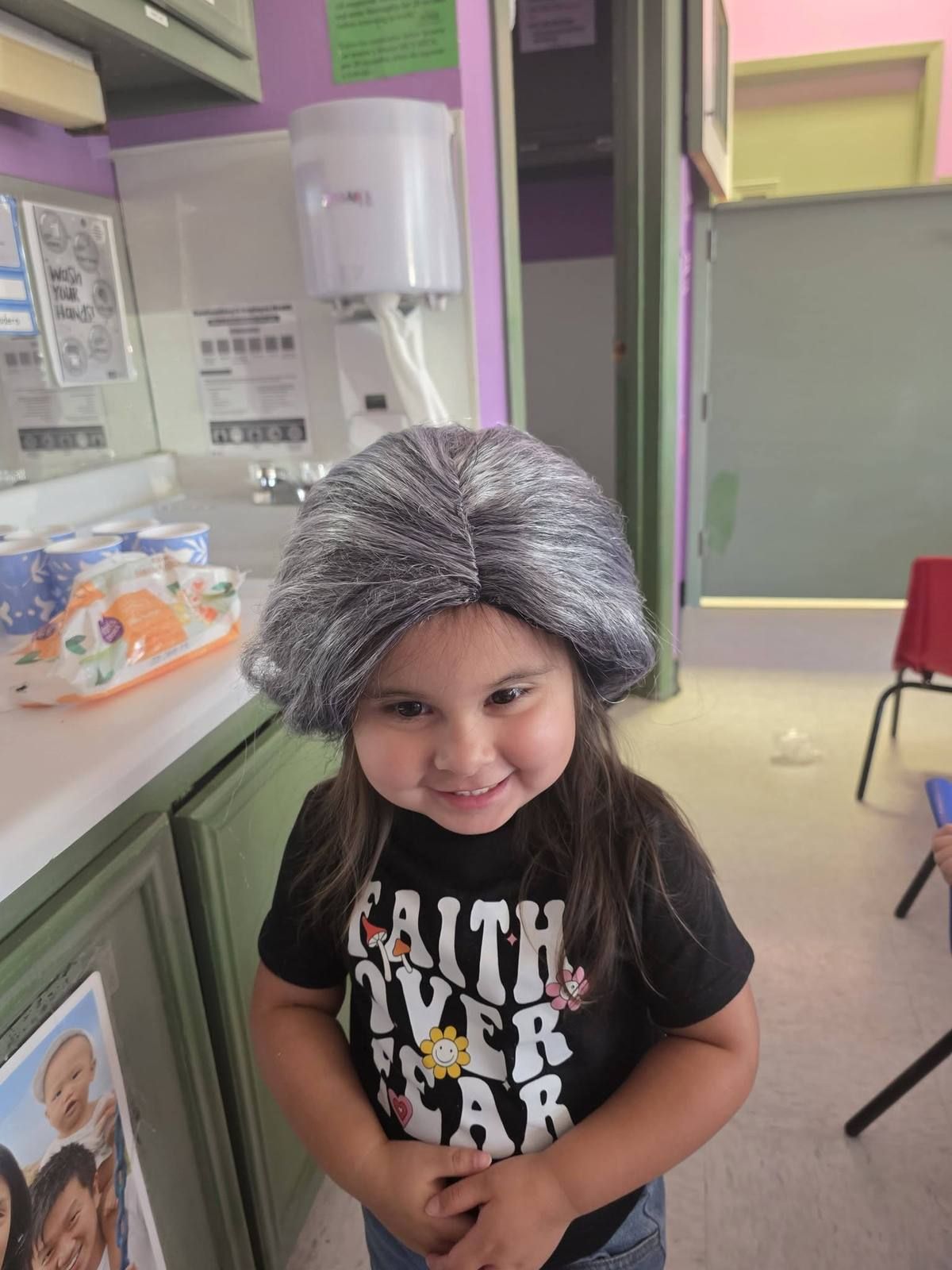 A preschooler smiling in a gray grandma wig