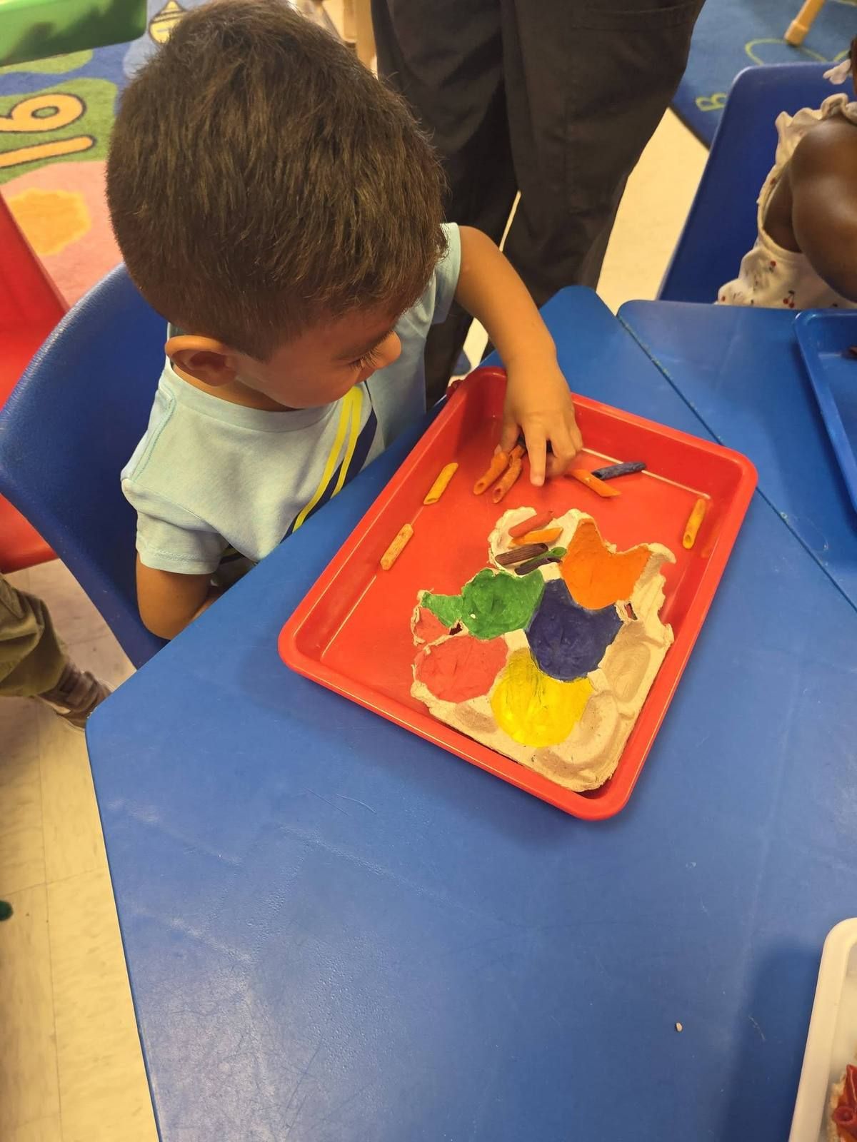 A toddler working on a play dough tray