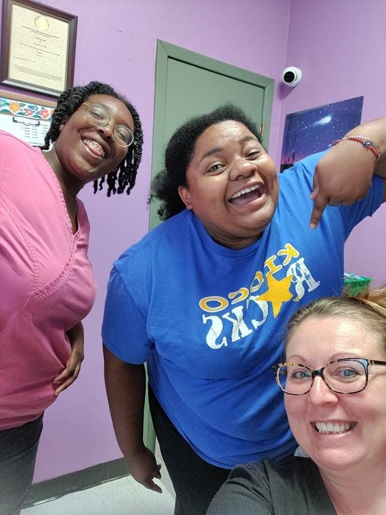 Three teachers smiling together in a classroom selfie
