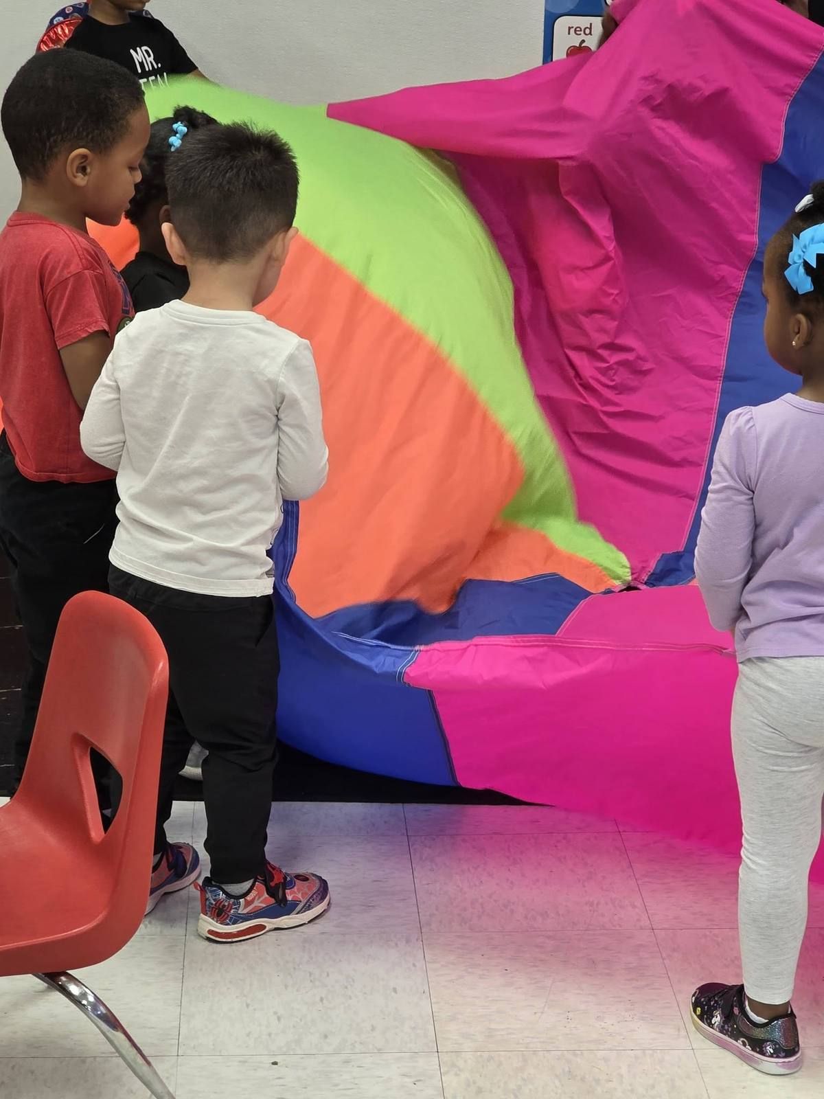 Toddlers playing with a big colorful parachute