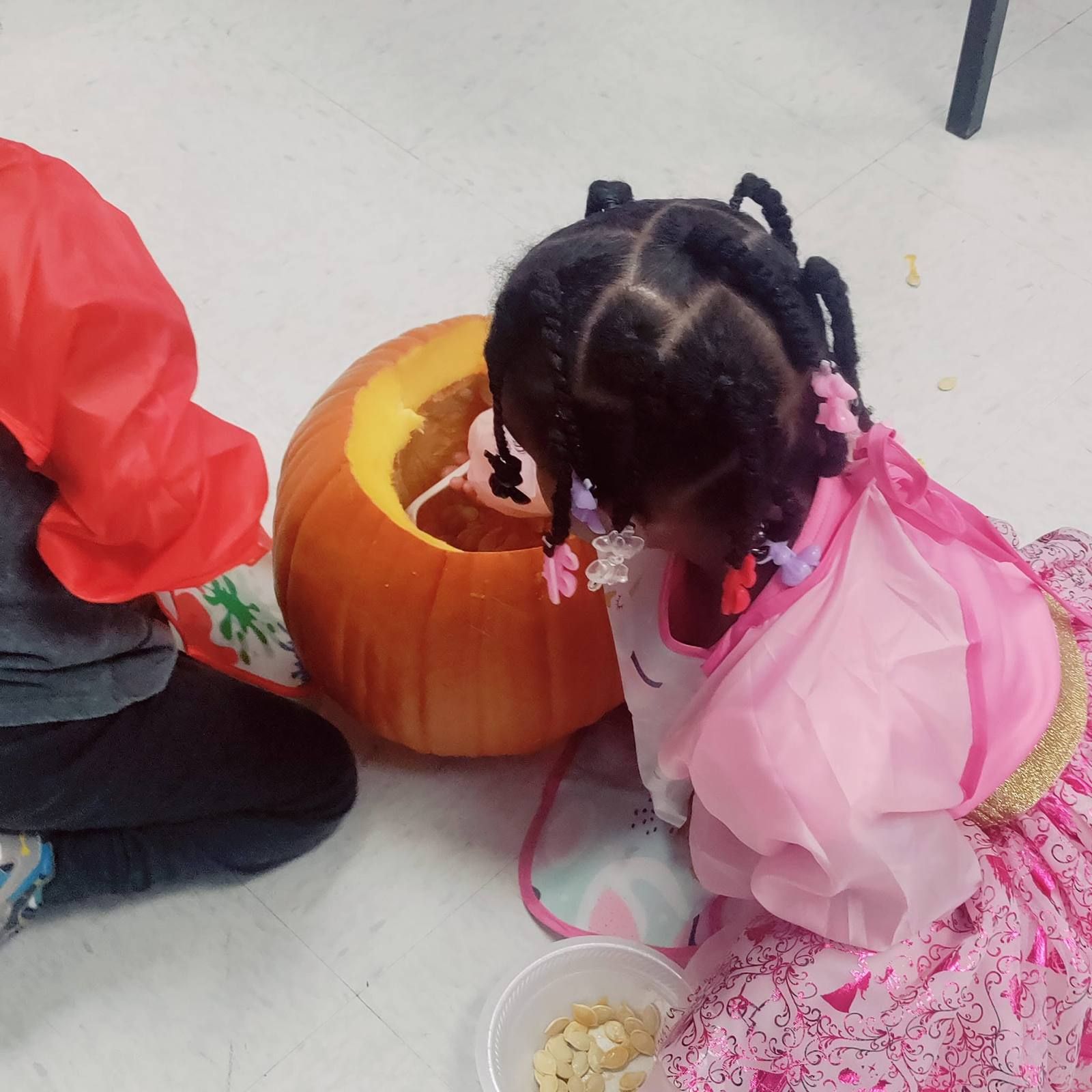 A little girl in a princess dress peeking into a pumpkin